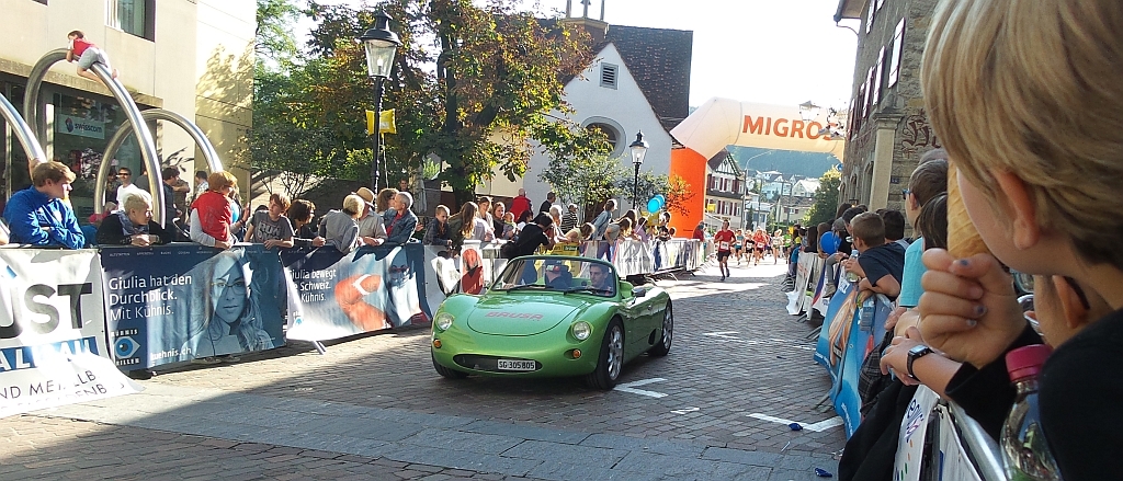 Das Führungsfahrzeug, ein Elektromobil, kündigt den Zuschauern in der Marktgasse die Spitze des Laufes an.