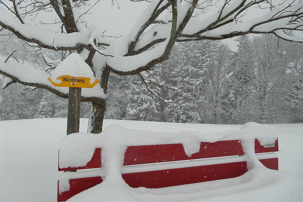 Tiefverschneite Bank am Wanderweg