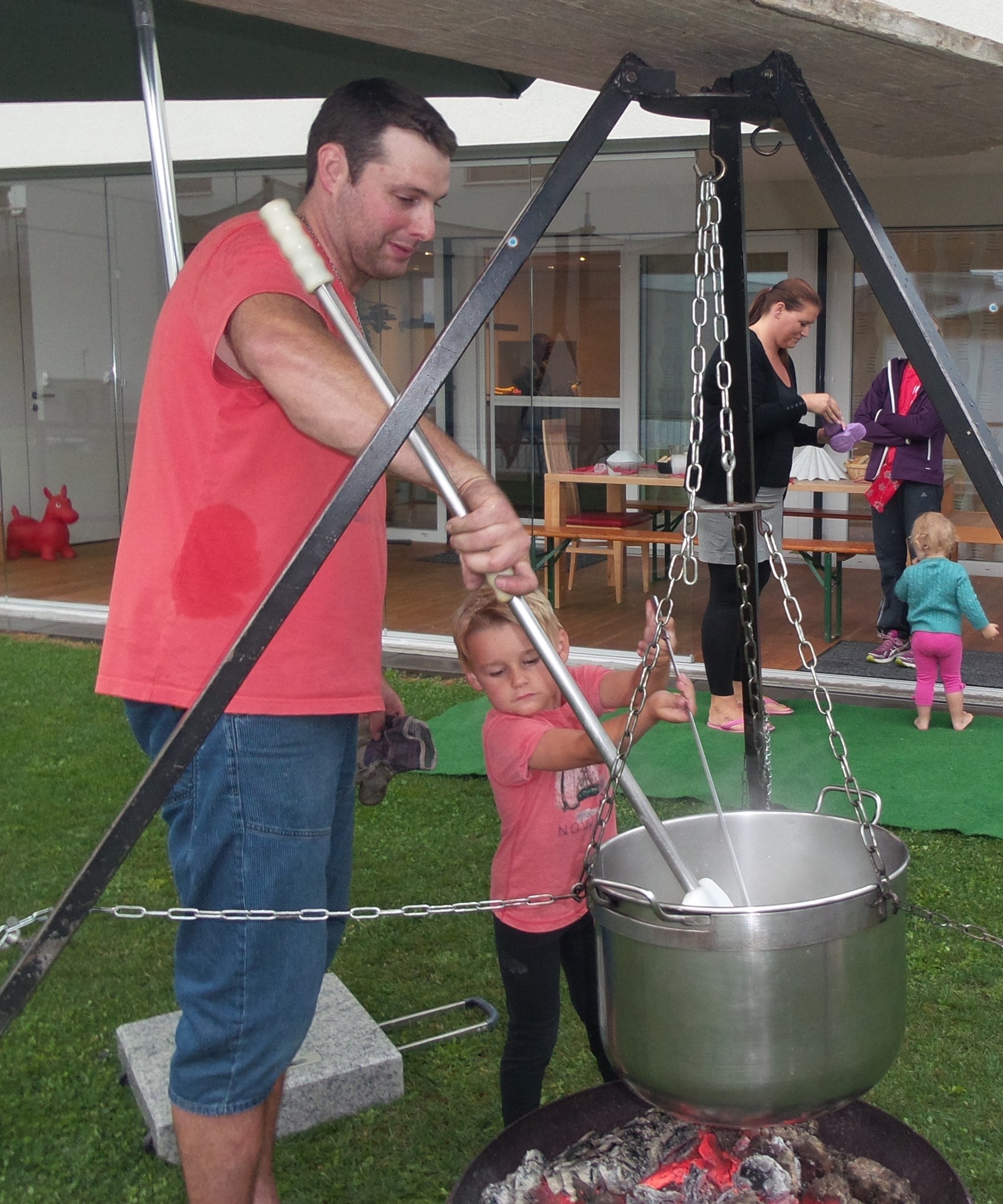 Roland rührt mit grosser Kelle in grossem Kessel und auf grossem Feuer das Fondue